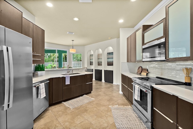 kitchen with decorative backsplash, dark brown cabinetry, stainless steel appliances, sink, and hanging light fixtures