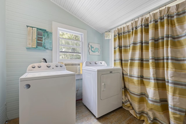 clothes washing area featuring wooden walls and washer and clothes dryer