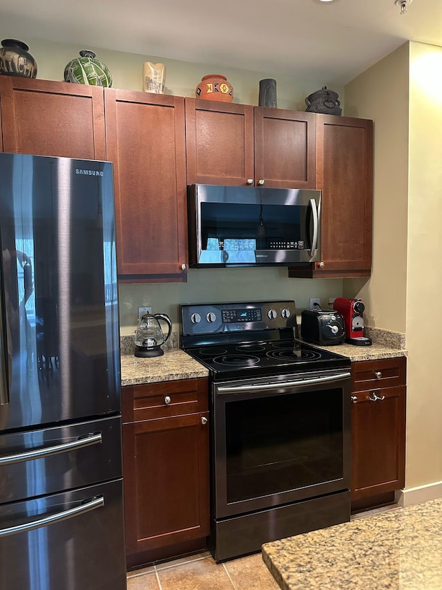 kitchen with stainless steel appliances, light stone countertops, and light tile patterned flooring