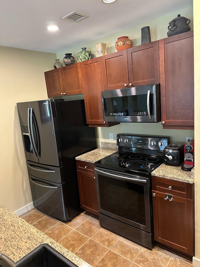 kitchen featuring light tile patterned floors, stainless steel appliances, light stone counters, and visible vents