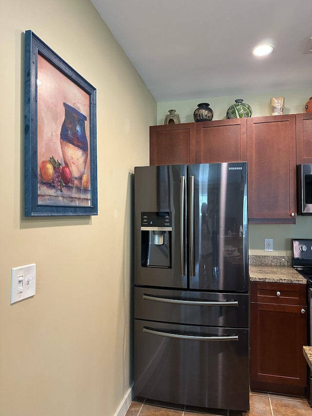 kitchen with light tile patterned floors, baseboards, light stone counters, and appliances with stainless steel finishes