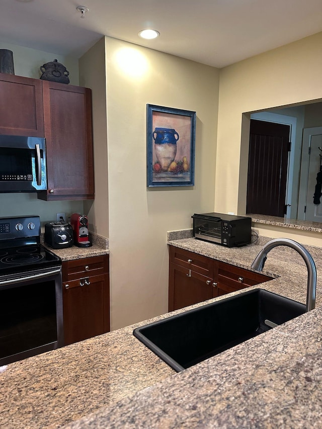 kitchen featuring recessed lighting, light stone countertops, stainless steel appliances, and a sink