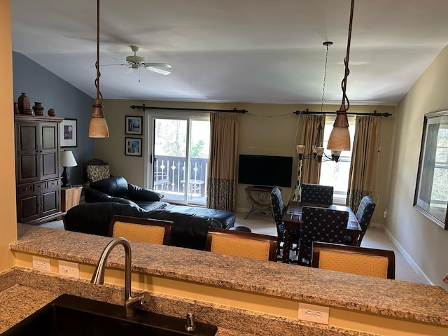 living room featuring baseboards, a ceiling fan, and vaulted ceiling