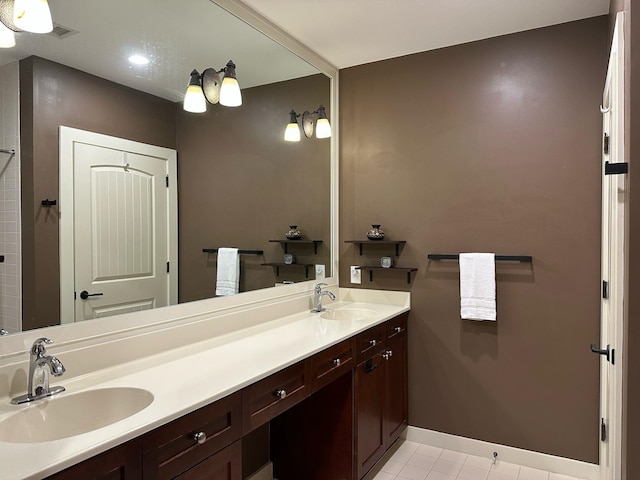 bathroom with a sink, visible vents, baseboards, and double vanity