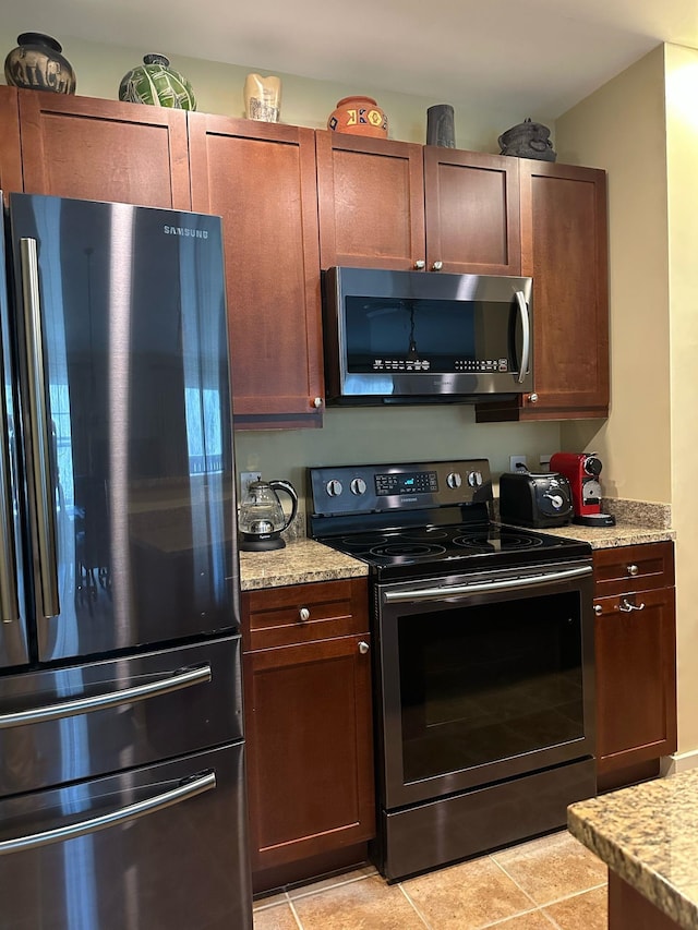 kitchen with light tile patterned flooring, light stone countertops, and appliances with stainless steel finishes