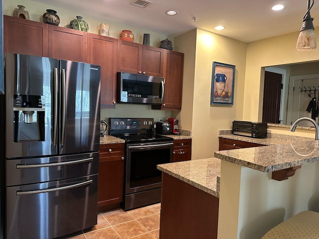 kitchen with a breakfast bar, recessed lighting, appliances with stainless steel finishes, light tile patterned flooring, and hanging light fixtures