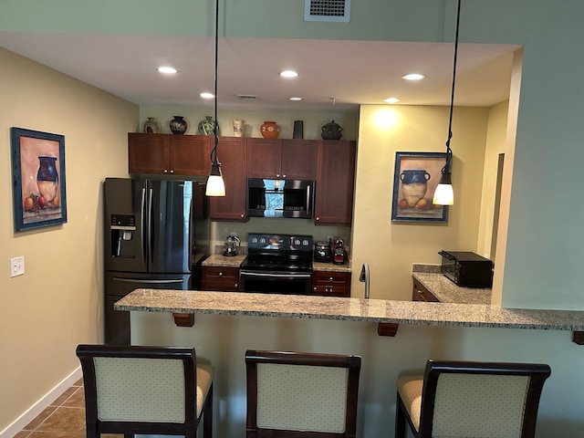 kitchen with hanging light fixtures, black appliances, a kitchen breakfast bar, and visible vents