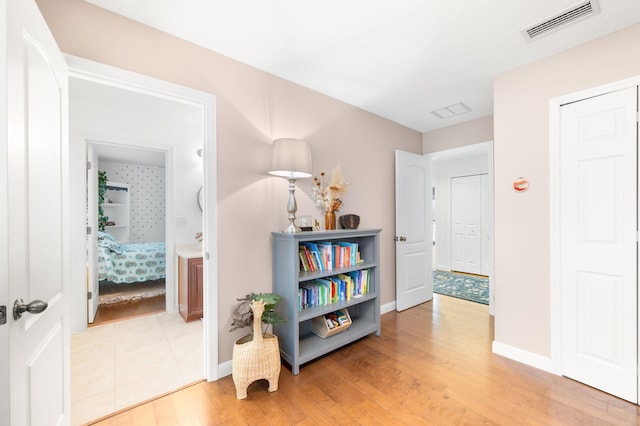 corridor featuring light wood-type flooring, visible vents, and baseboards