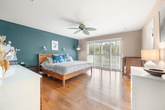 bedroom featuring access to outside, ceiling fan, a textured ceiling, and light wood finished floors