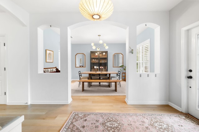 foyer with baseboards, arched walkways, and wood finished floors