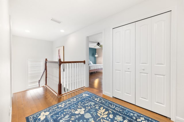 corridor featuring visible vents, wood finished floors, and an upstairs landing