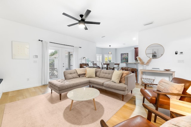 living room with baseboards, visible vents, a ceiling fan, light wood-style flooring, and french doors