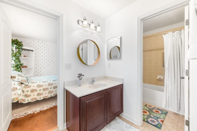 ensuite bathroom with connected bathroom, a textured ceiling, and vanity