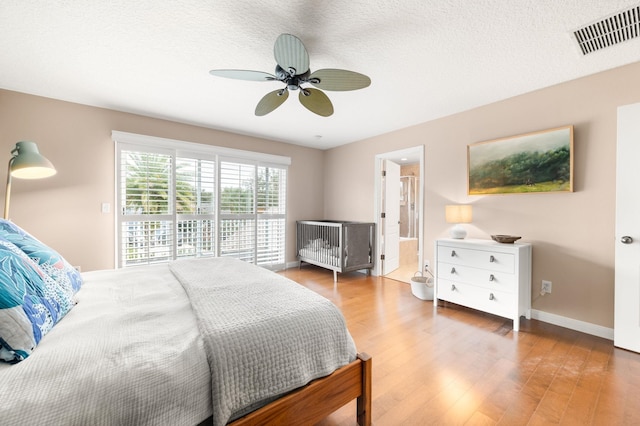 bedroom featuring baseboards, visible vents, ceiling fan, wood finished floors, and a textured ceiling