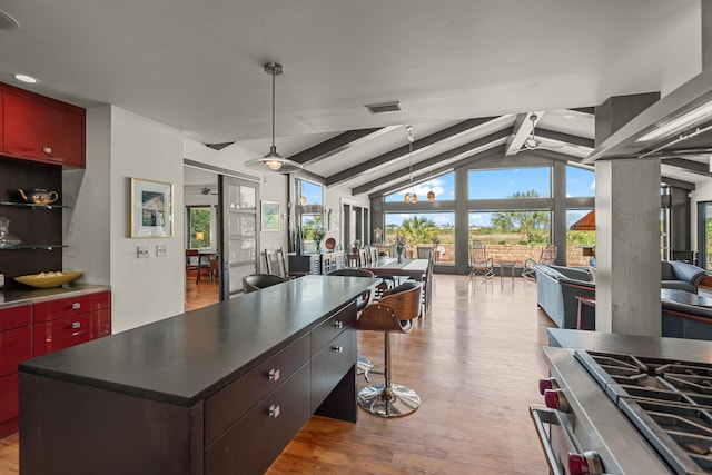 kitchen featuring dark countertops, light wood-style flooring, vaulted ceiling with beams, a kitchen island, and visible vents