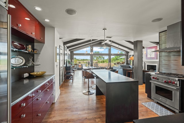 kitchen featuring wall chimney range hood, recessed lighting, a ceiling fan, light wood finished floors, and premium stove