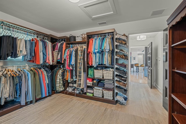 spacious closet featuring visible vents, attic access, and wood finished floors