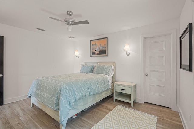 bedroom featuring a ceiling fan, baseboards, visible vents, and wood finished floors