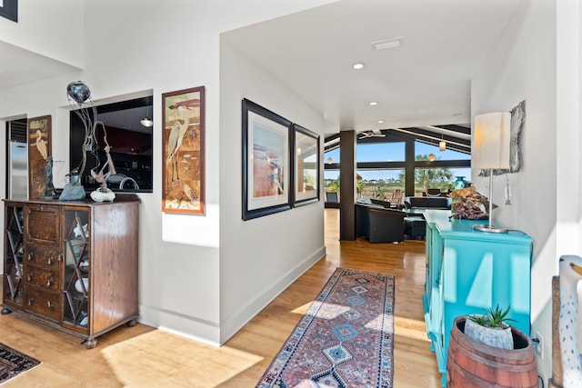 hall with baseboards, wood finished floors, and lofted ceiling