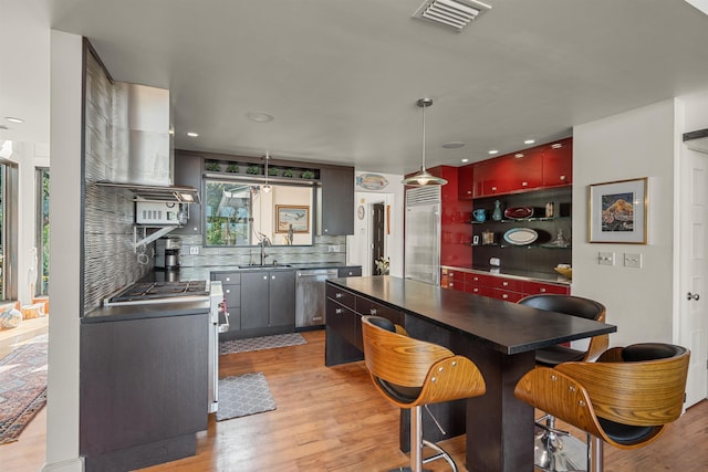 kitchen with visible vents, a sink, light wood-style flooring, and tasteful backsplash