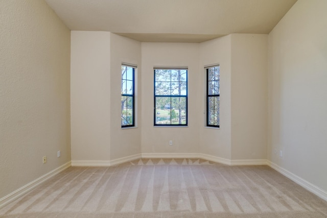 spare room featuring baseboards and light colored carpet