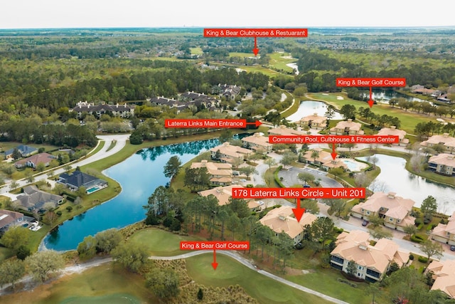 drone / aerial view with a residential view, a wooded view, view of golf course, and a water view