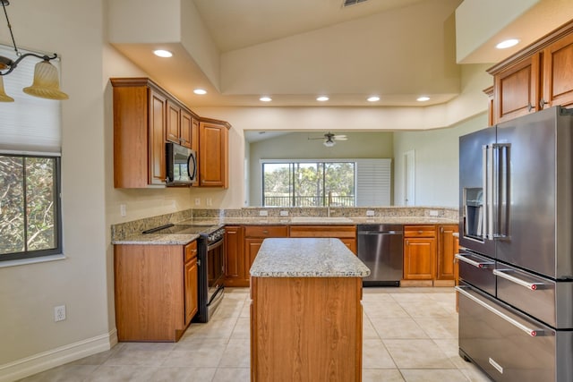 kitchen featuring brown cabinetry, a sink, ceiling fan, appliances with stainless steel finishes, and a center island