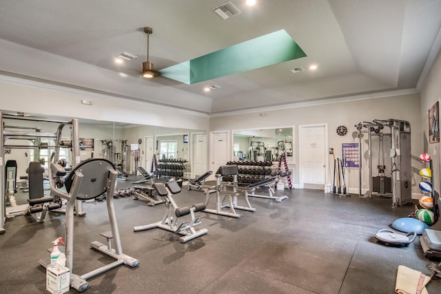 exercise room featuring a tray ceiling, visible vents, ornamental molding, and a ceiling fan