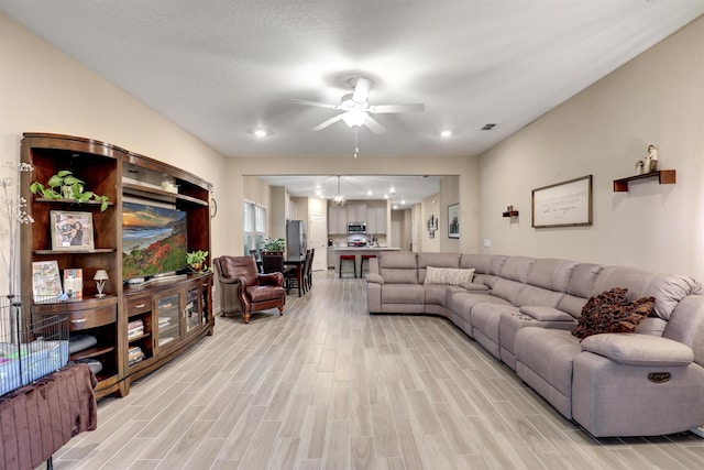 living room with light wood-type flooring, visible vents, and a ceiling fan