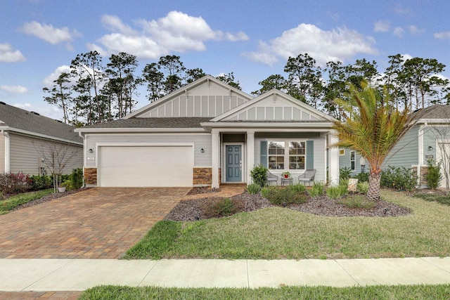 view of front facade featuring an attached garage, decorative driveway, a front lawn, and board and batten siding