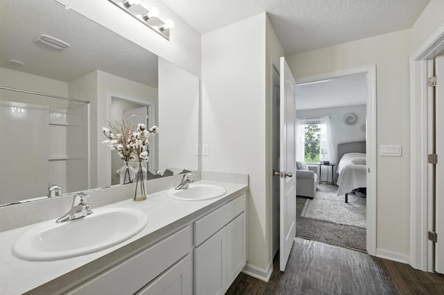 313 Caminha Rd, Saint Augustine, FL 32084 - full bathroom with double vanity, ensuite bath, wood finished floors, a textured ceiling, and a shower