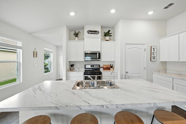 313 Caminha Rd, Saint Augustine, FL 32084 - kitchen featuring stainless steel appliances, a breakfast bar, white cabinets, lofted ceiling, and a kitchen island with sink