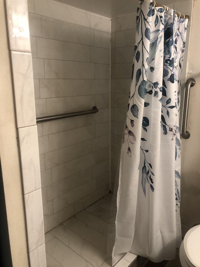 bathroom featuring a shower with shower curtain, tile patterned flooring, and toilet