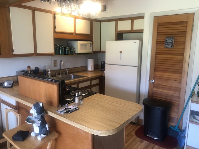 kitchen featuring kitchen peninsula, dark hardwood / wood-style flooring, white appliances, and sink