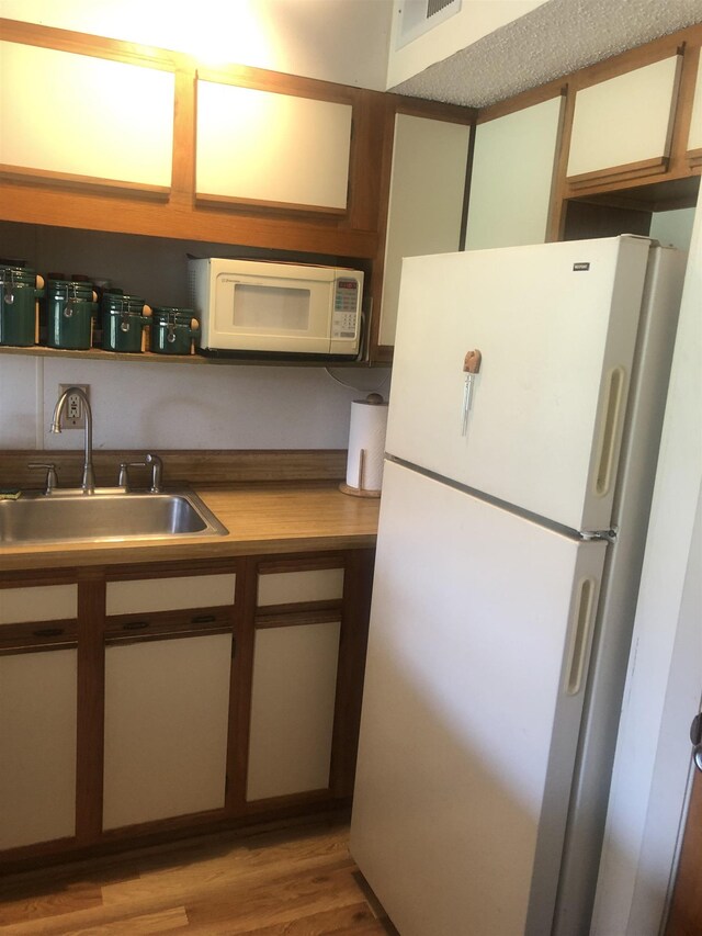 kitchen featuring sink, light hardwood / wood-style floors, and white appliances