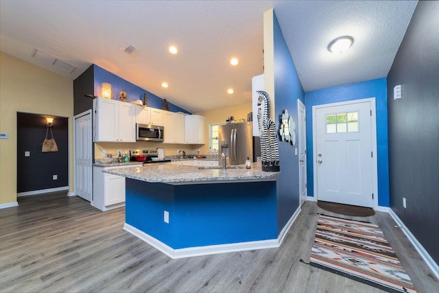 4420 Cedar Ford Blvd, Hastings, FL 32145 - kitchen featuring appliances with stainless steel finishes, light wood-style flooring, white cabinetry, a peninsula, and light stone counters