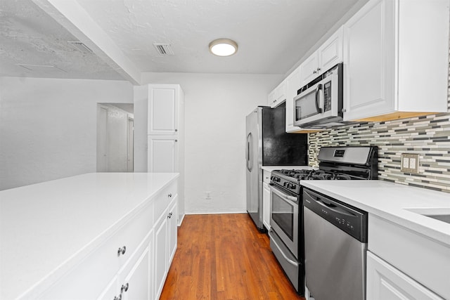 1316 NE 9th St, Gainesville, FL 32605 - kitchen featuring appliances with stainless steel finishes, decorative backsplash, white cabinets, light countertops, and wood finished floors