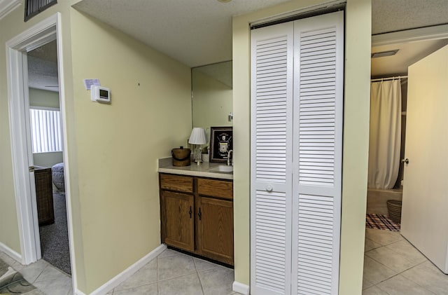 hall featuring light tile patterned floors, sink, and a textured ceiling