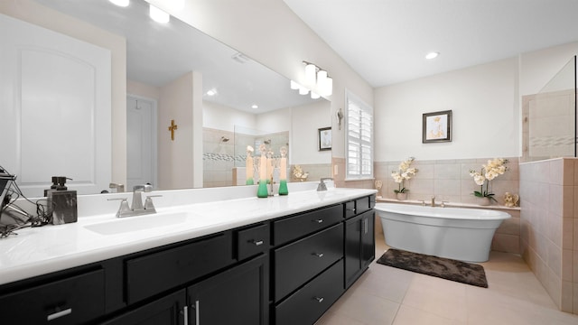 bathroom with tile patterned flooring, vanity, tile walls, and plus walk in shower