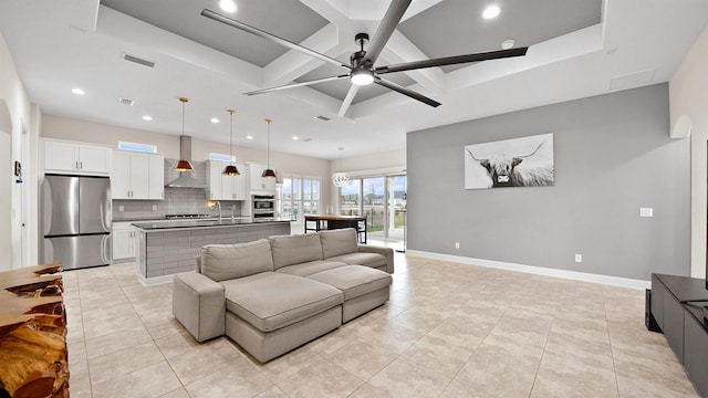 tiled living room with a tray ceiling, ceiling fan, and sink