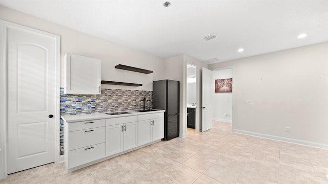 kitchen featuring decorative backsplash, black appliances, sink, light tile patterned floors, and white cabinetry