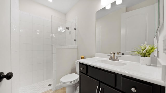 bathroom featuring tiled shower, vanity, and toilet