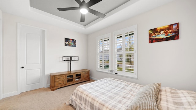 carpeted bedroom featuring a tray ceiling and ceiling fan