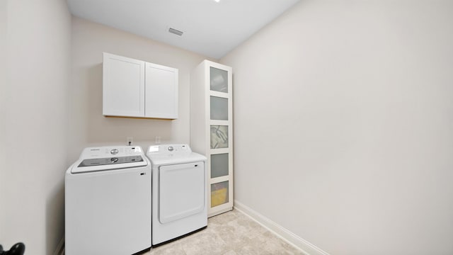 clothes washing area featuring washing machine and clothes dryer and cabinets