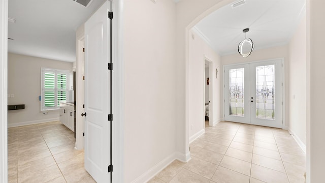 foyer entrance with plenty of natural light, light tile patterned floors, french doors, and ornamental molding