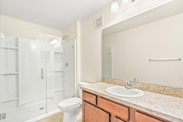 bathroom featuring toilet, vanity, tile patterned floors, a textured ceiling, and a shower with door