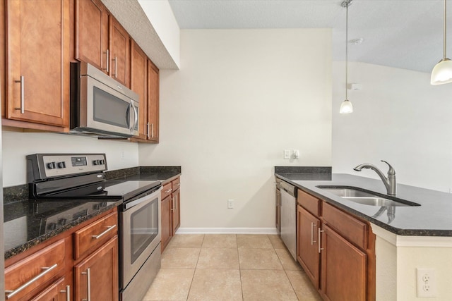 kitchen featuring light tile patterned floors, stainless steel appliances, dark stone counters, hanging light fixtures, and sink