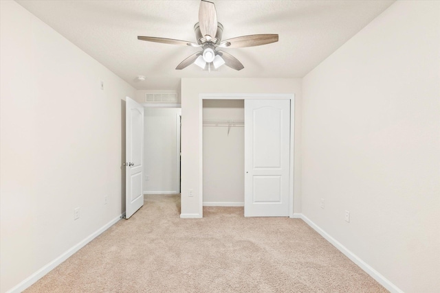 unfurnished bedroom featuring ceiling fan, a textured ceiling, a closet, and light carpet