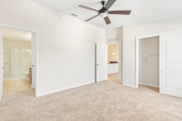 unfurnished bedroom with ceiling fan, light carpet, a closet, and ensuite bathroom