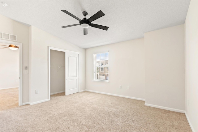 unfurnished bedroom with ceiling fan, light colored carpet, a closet, and a textured ceiling